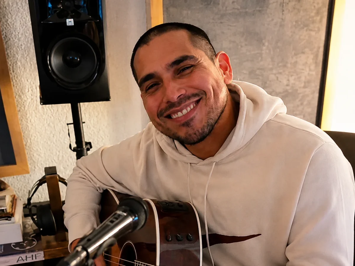 Espinoza Paz sonriendo mientras toca una guitarra durante una sesión musical.