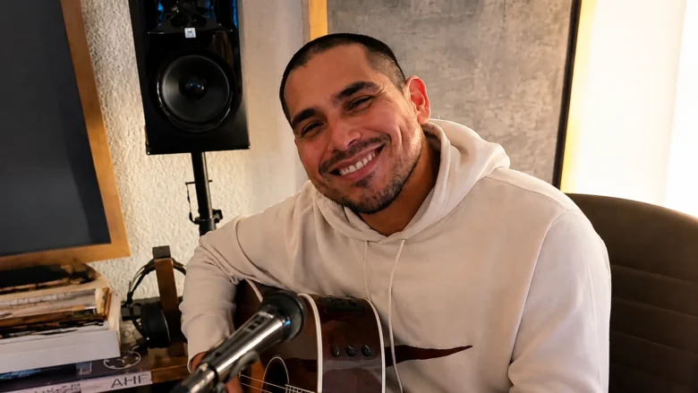 Espinoza Paz sonriendo mientras toca una guitarra durante una sesión musical.