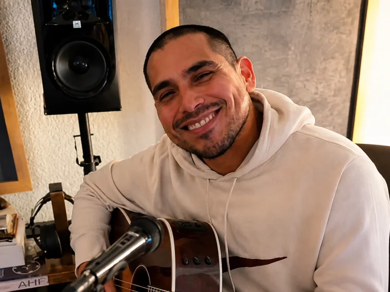 Espinoza Paz sonriendo mientras toca una guitarra durante una sesión musical.